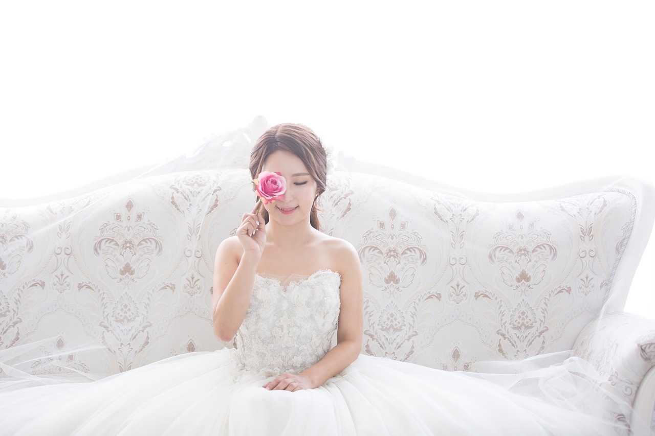 Novia con una rosa rosa en un sofá clásico